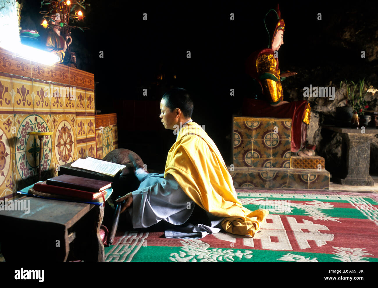 Female buddhist monk praying in a cave temple near Ninh Binh, Vietnam Stock Photo