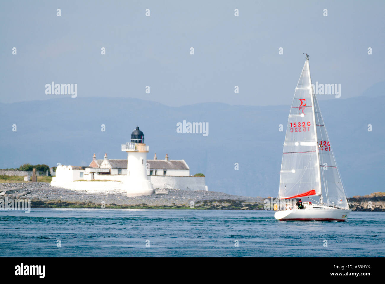 Yacht sailing past lighthouse Stock Photo