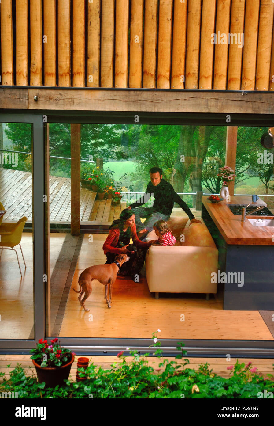 A YOUNG FAMILY IN A MODERN HOUSE WITH LARGE GLASS SLIDING WINDOWS UK Stock Photo