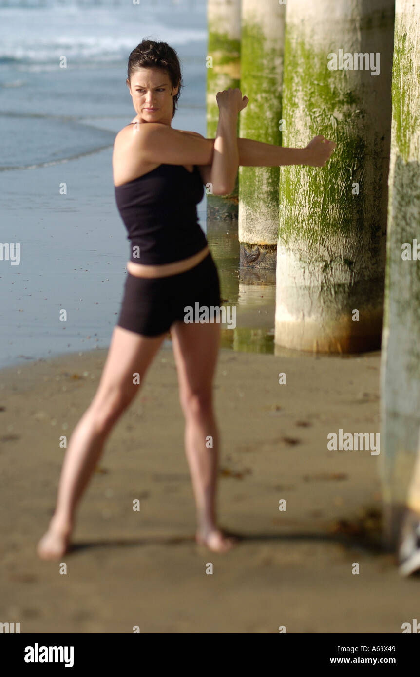 A woman stretching and getting ready to run on the beach Stock Photo