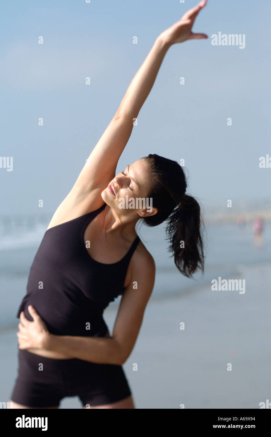 A woman stretching and getting ready to run on the beach Stock Photo