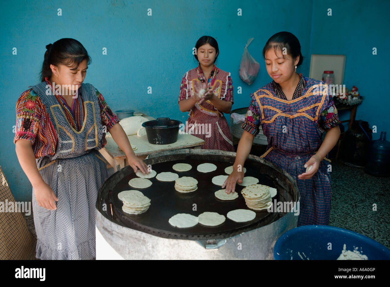 Three women making and frying tortillas from corn flour Panajachel