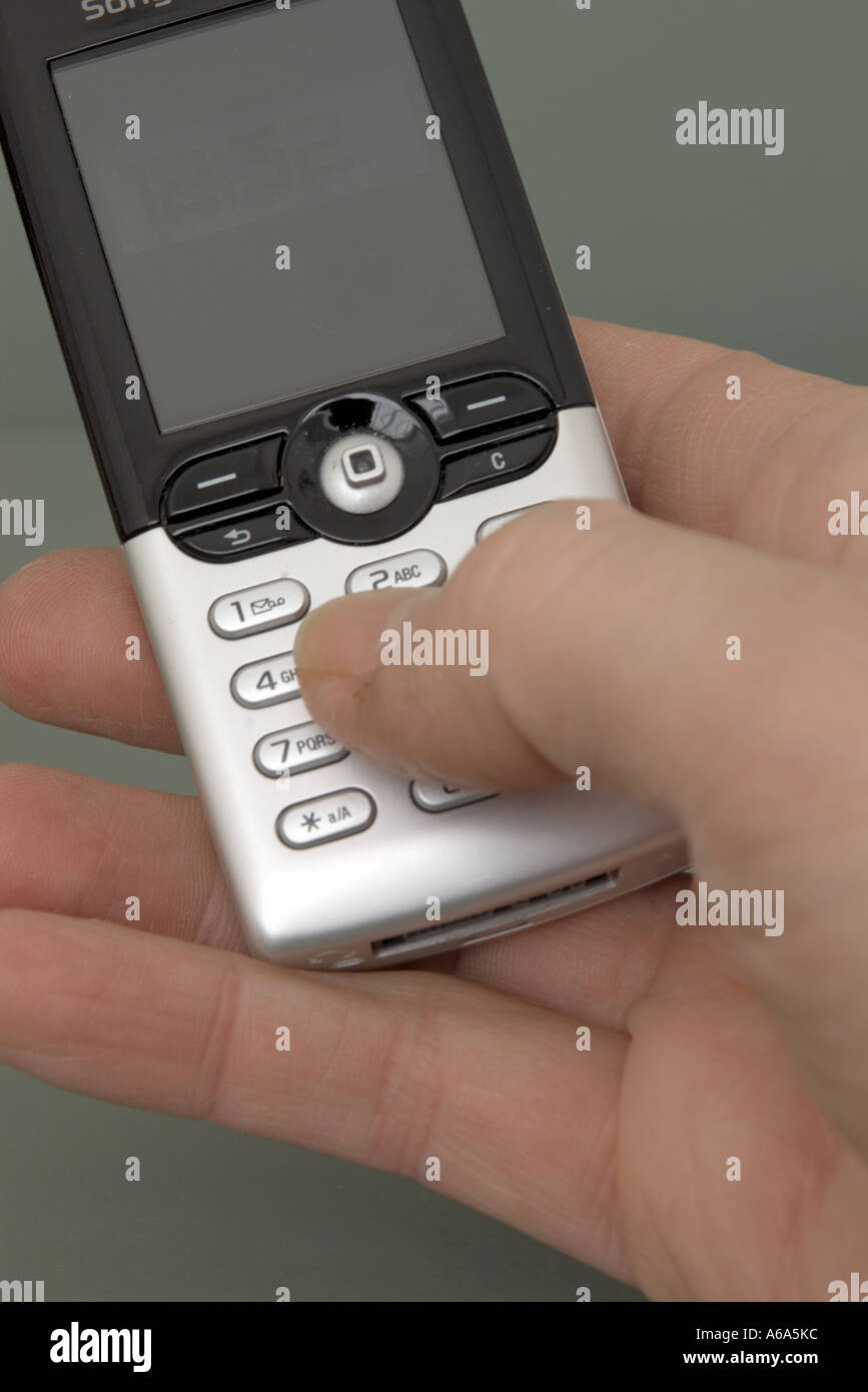 man keying into silver mobile phone using thumb Stock Photo