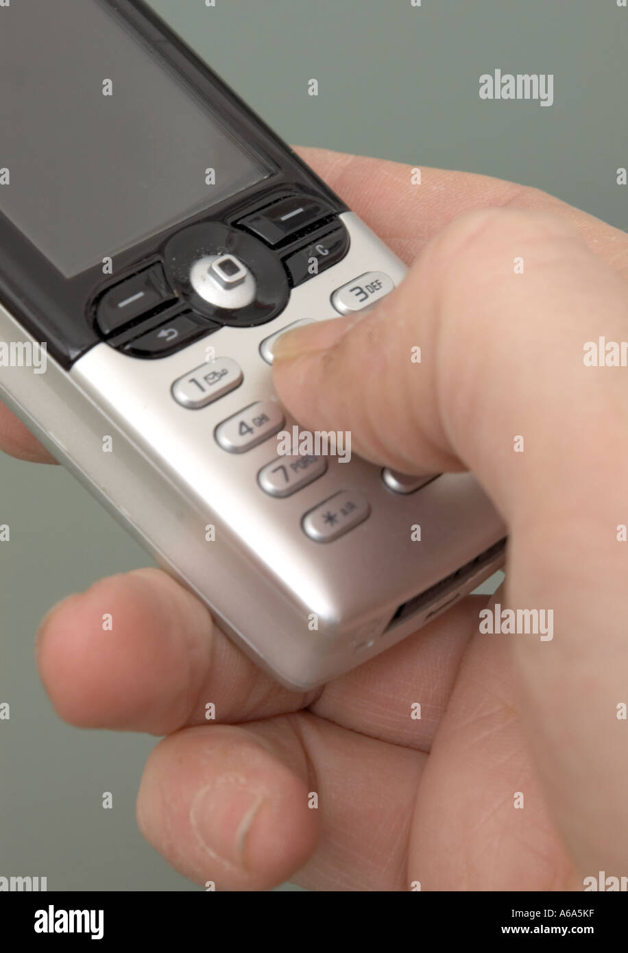 man keying into silver mobile phone using thumb Stock Photo