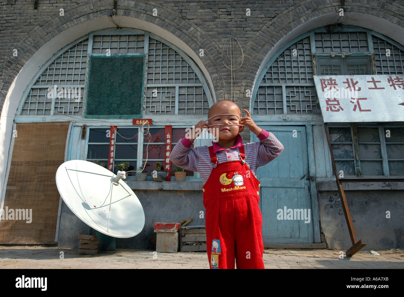 A little girl plays in front of a cave dwellings in northwest Yanan Shanxi China 2002 Stock Photo