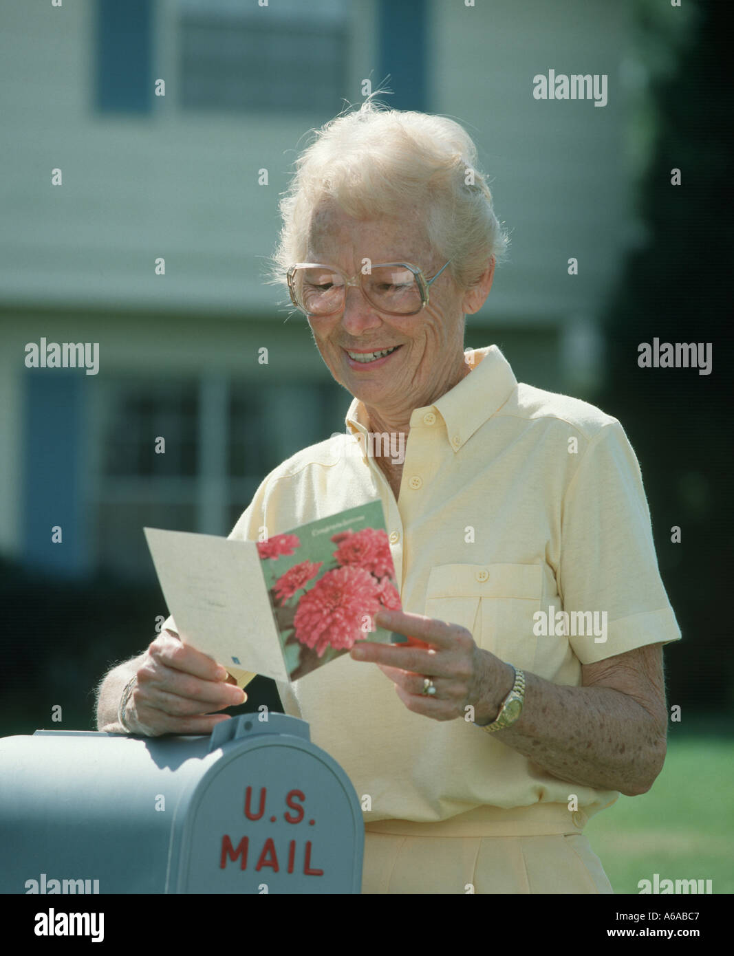 mature woman reading card at mailbox Stock Photo