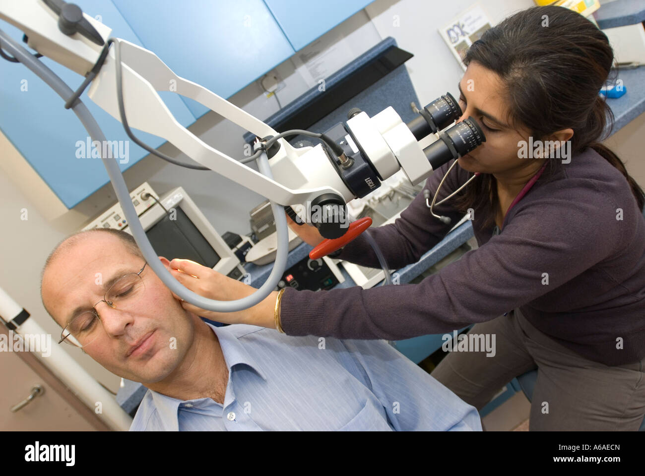 A female Asian doctor looks through a portable microscope to examine a ...