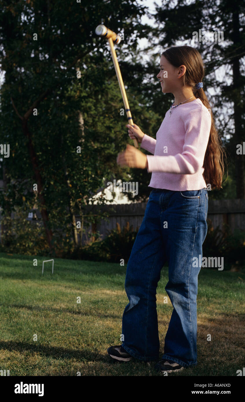 Young girl 12 yrs playing croquet in backyard with family celebrating her play Stock Photo Alamy