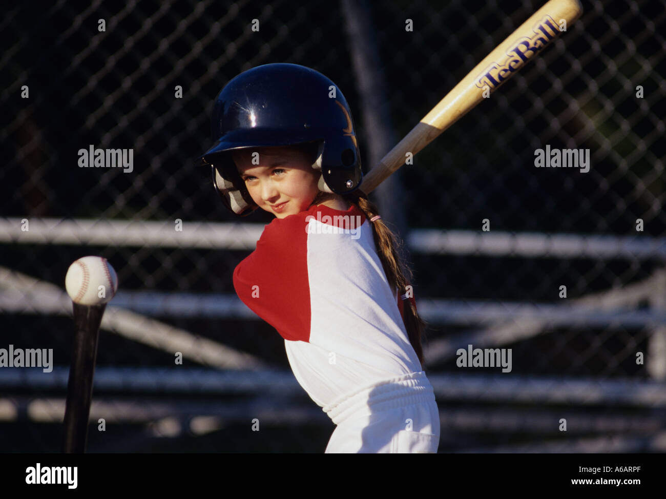 Young girl 7 swinging bat at ball on T concentrating on her swing with smile Stock Photo Alamy