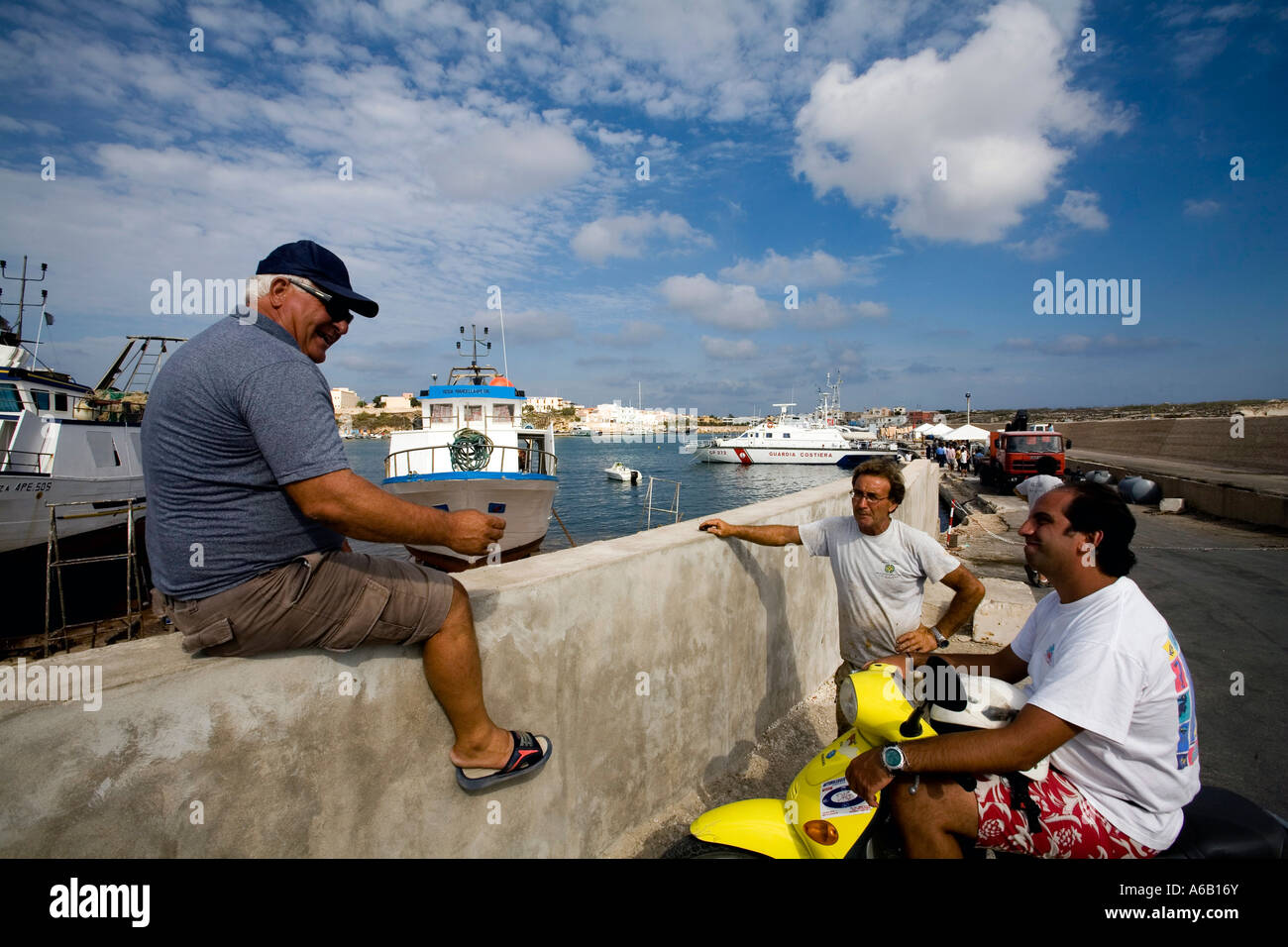 Local residents having a chat along the harbour Lampedusa Island Sicily Italy Stock Photo