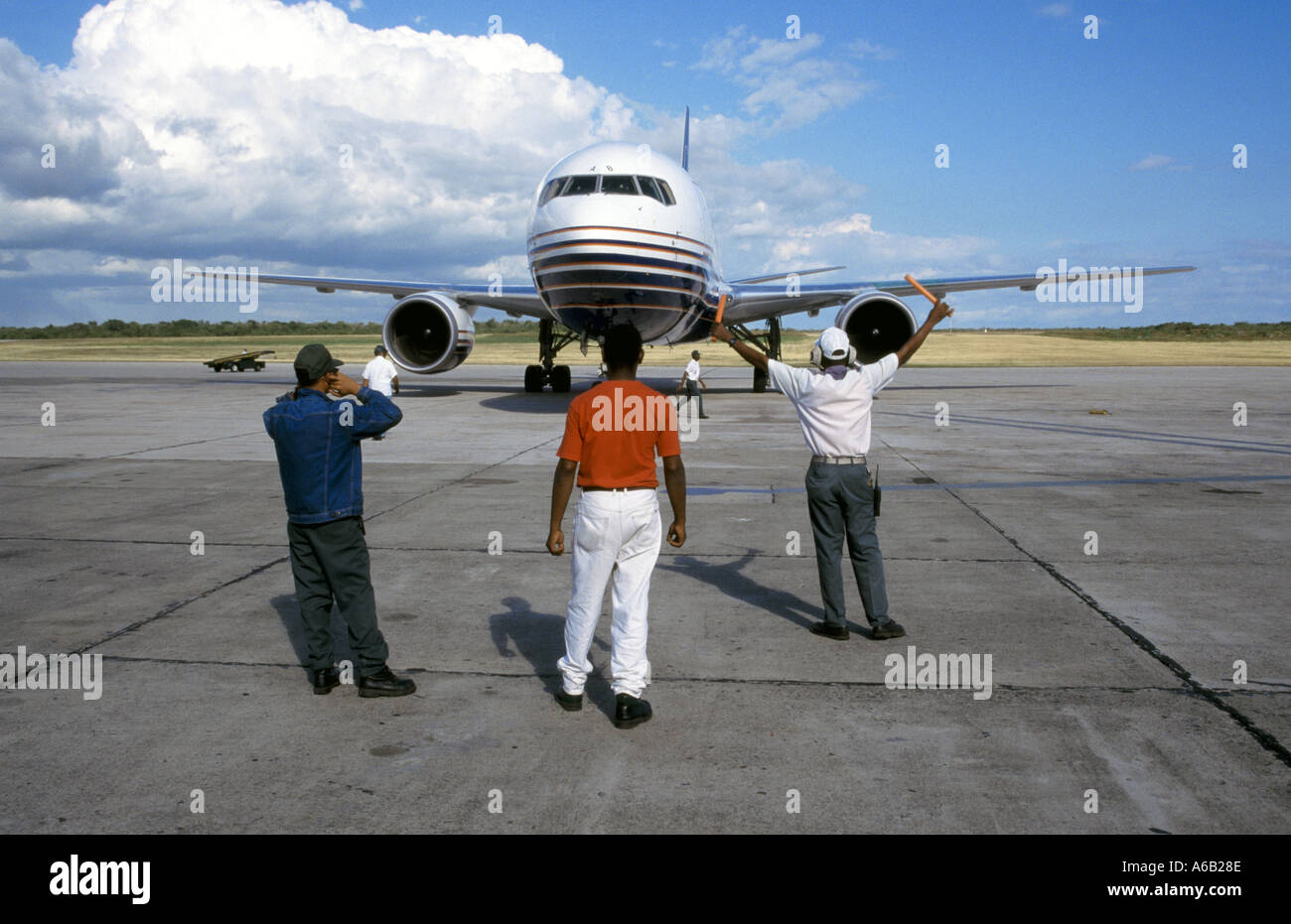 Plane & passengers arrive Santo Domingo Airport Britannia Airways Boeing jet aircraft directed by ground crew & hand held aircraft marshalling signals Stock Photo