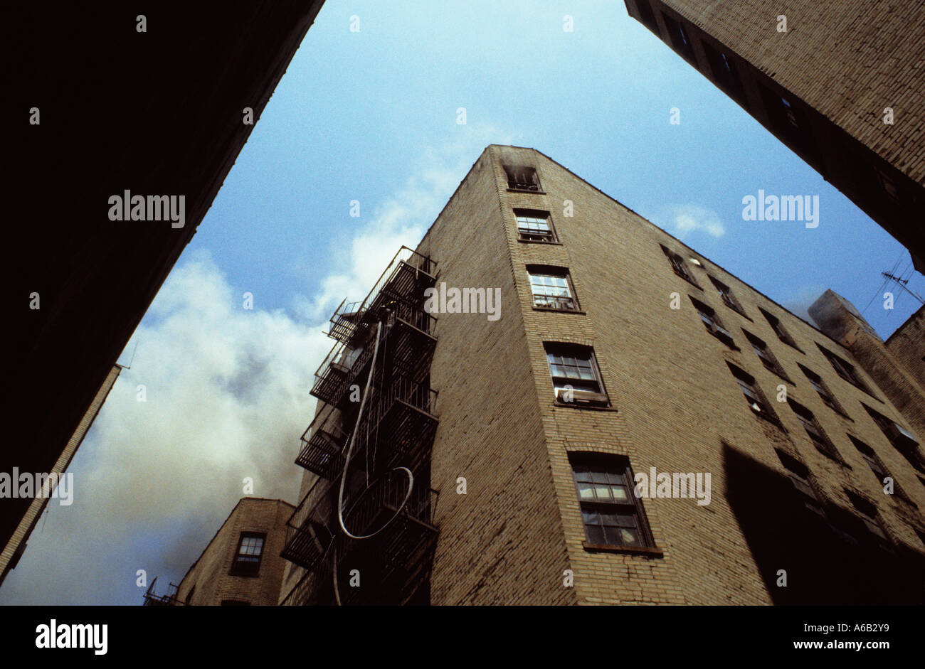 Hose being lifted by the New York fire department. Smoke coming out of a burning tenement building in The Bronx, New York City. Building on fire USA Stock Photo