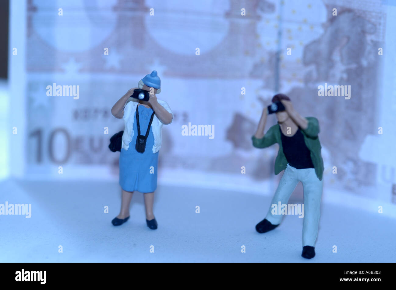 Miniature man and woman taking photos against a backdrop of a 10 Euro bill. Stock Photo