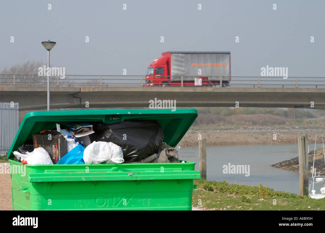 Overflowing industrial size rubbish bin on banks of the River Arun at
