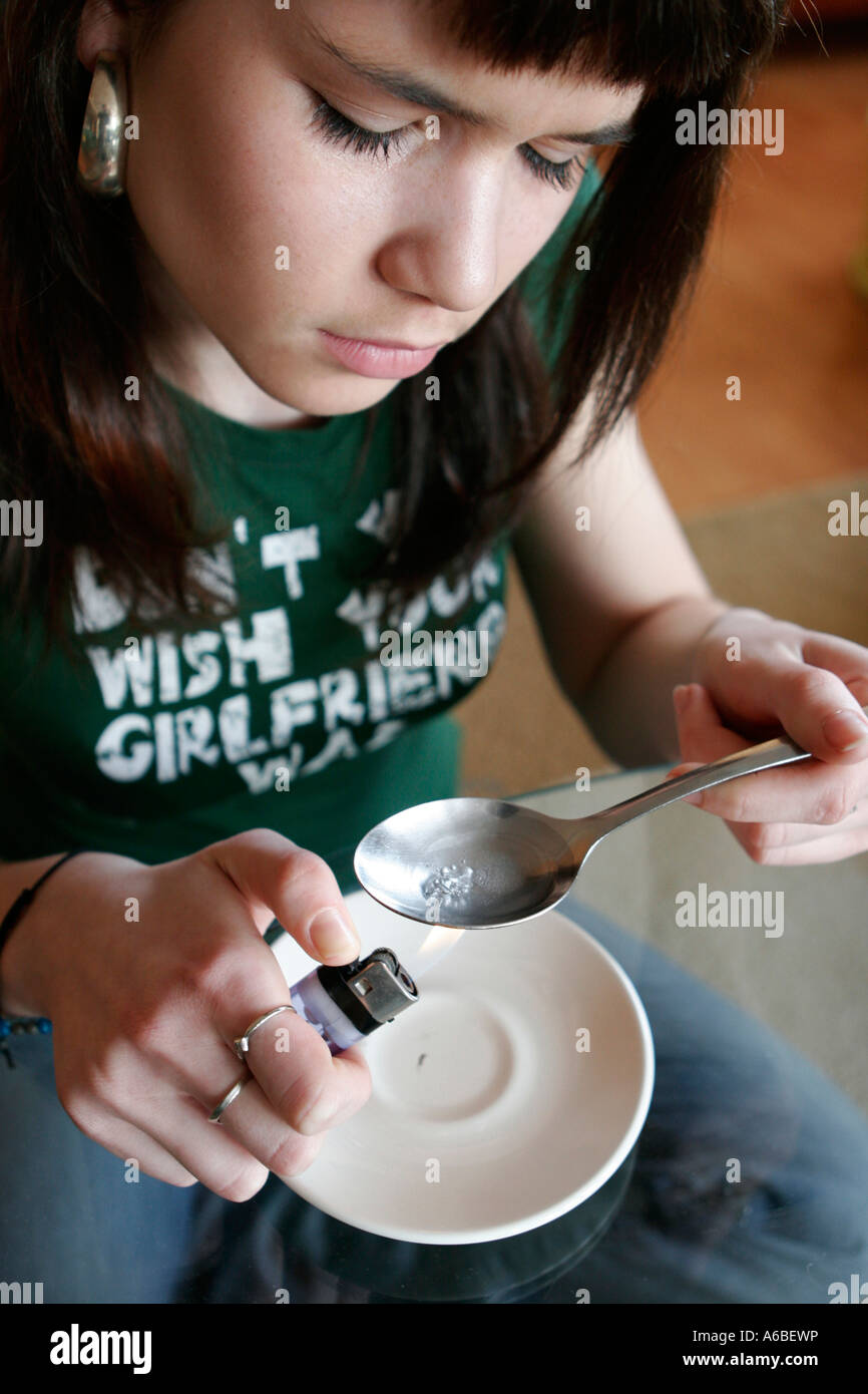 Teenage girl addict preparing heroin for injecting Stock Photo