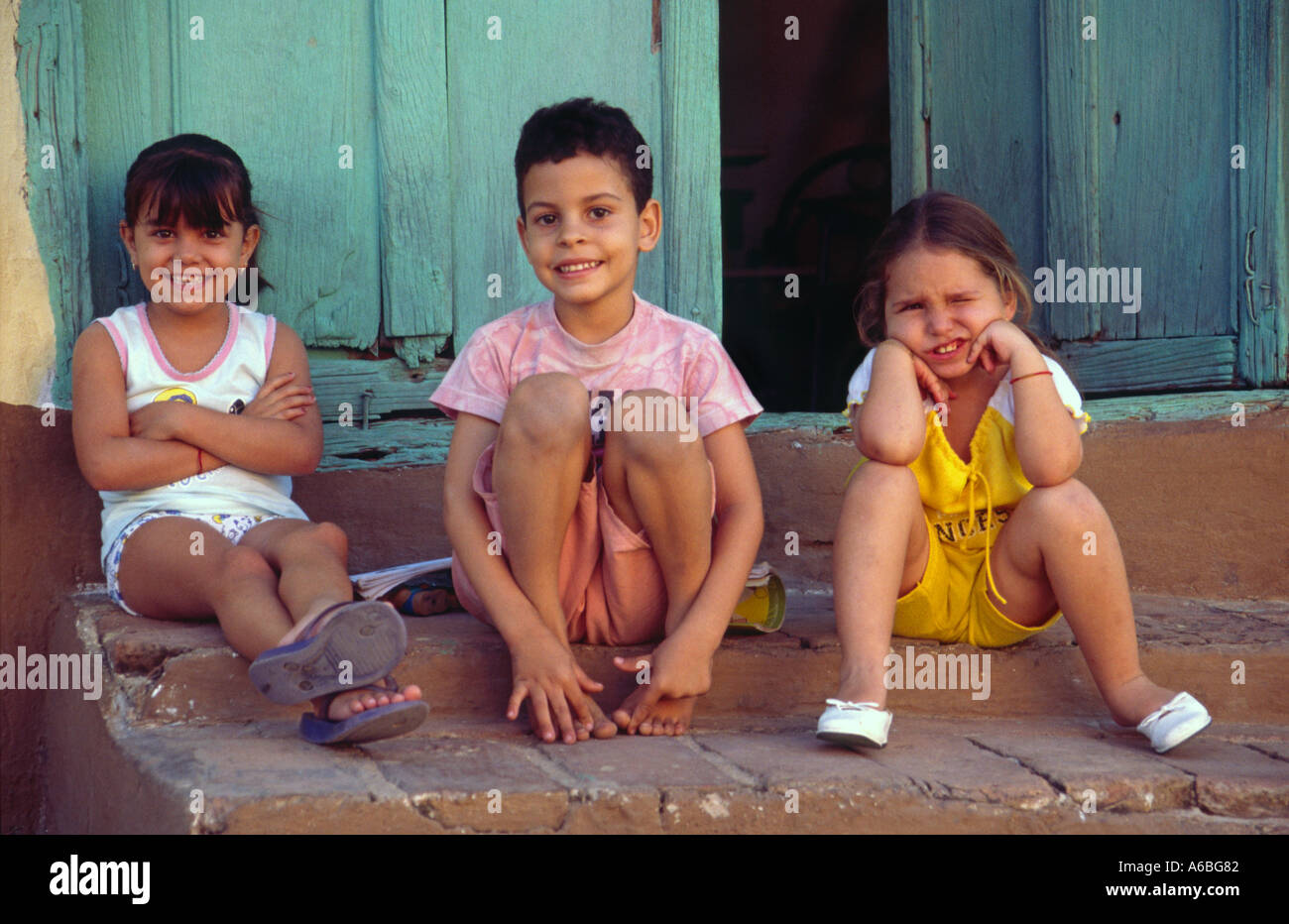 Three children sitting outside their house in Trinidad Cuba Stock Photo