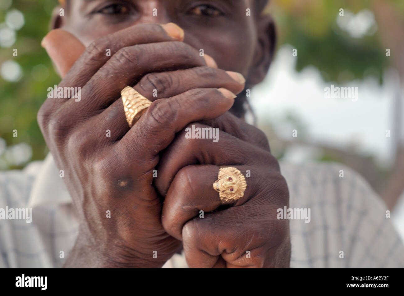 A color horizontal close up image of the hands of a rastafarian man cupped in front of his face while lighting something to smok Stock Photo