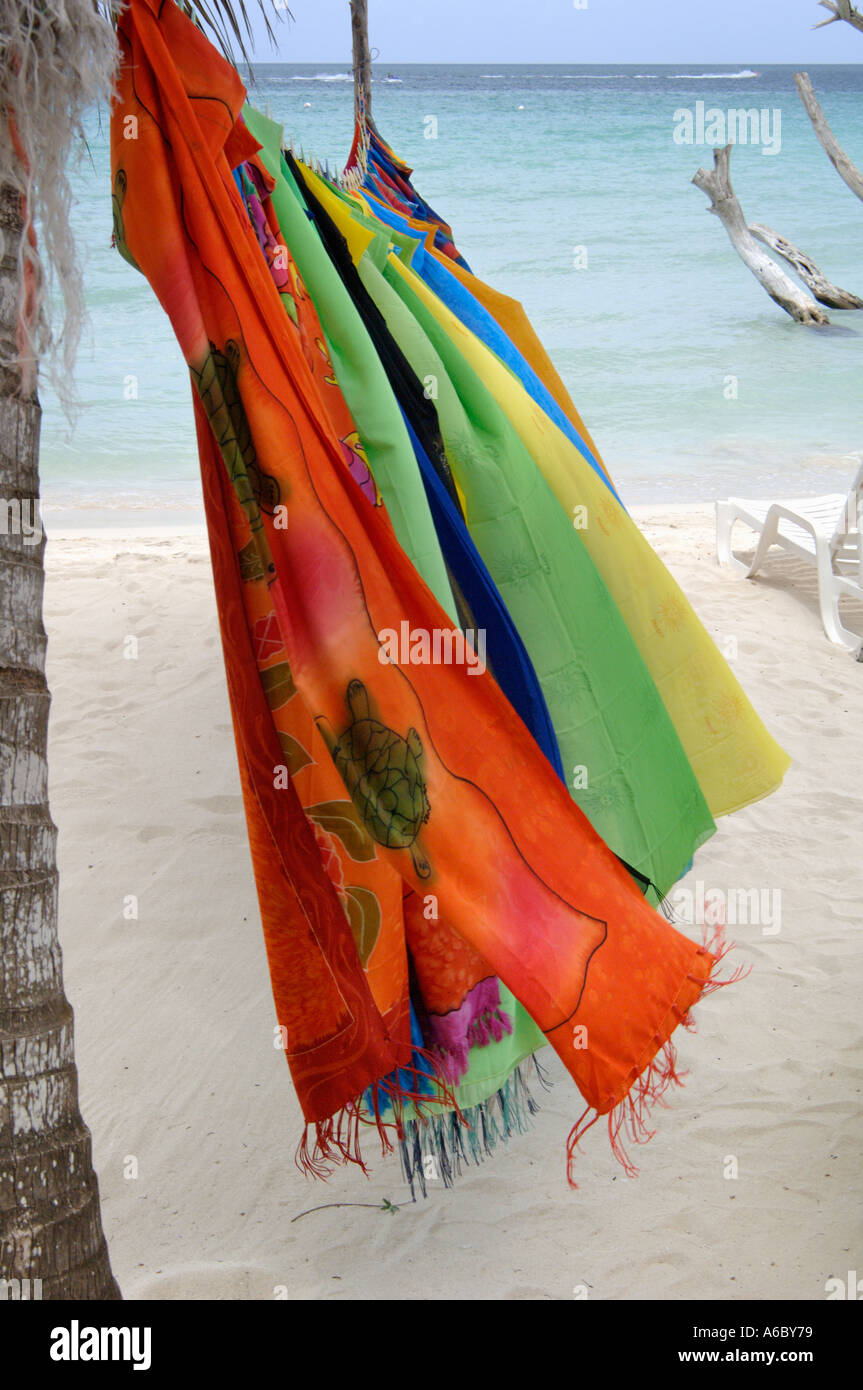 Vertical color photo of several colorful diaphanous scarves hanging from a line strung from palms Stock Photo