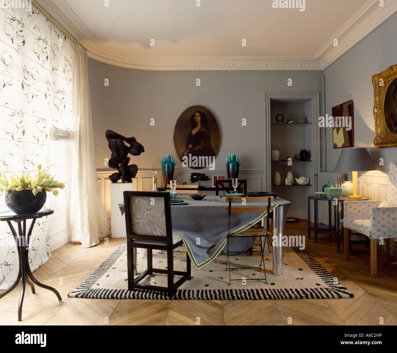 Assorted chairs in diningroom with sculpture and pictures on grey walls ...