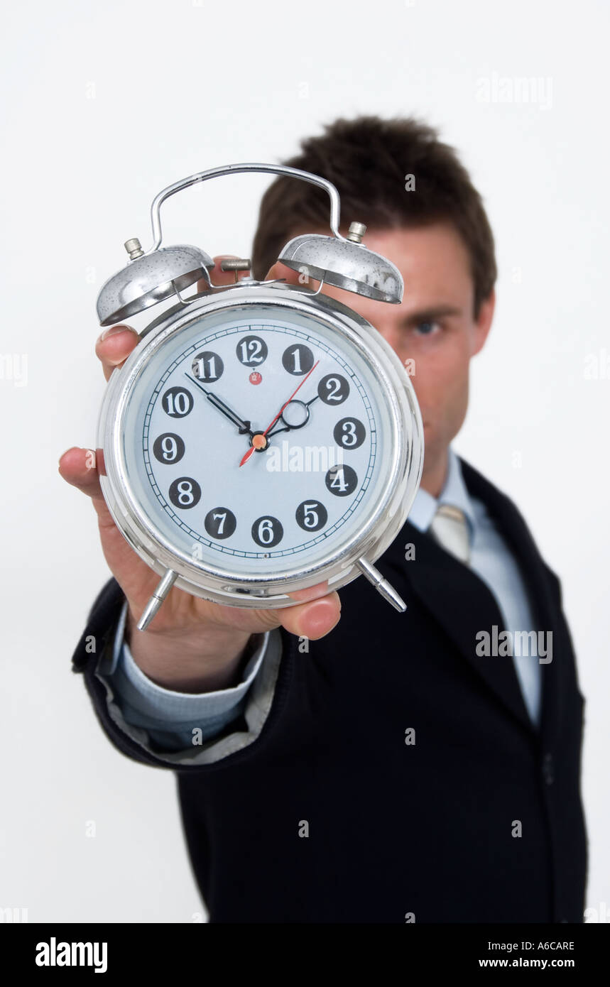 businessman holding up an alarm clock pushed for time time limit Stock