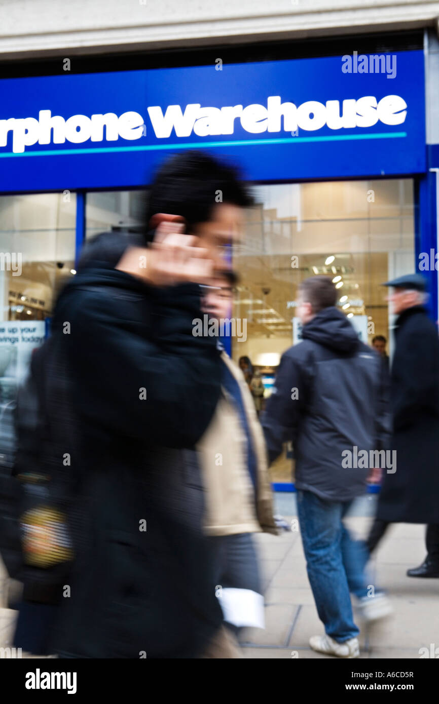 Man on mobile phone walks past Carphone Warehouse shop on Oxford Street Stock Photo