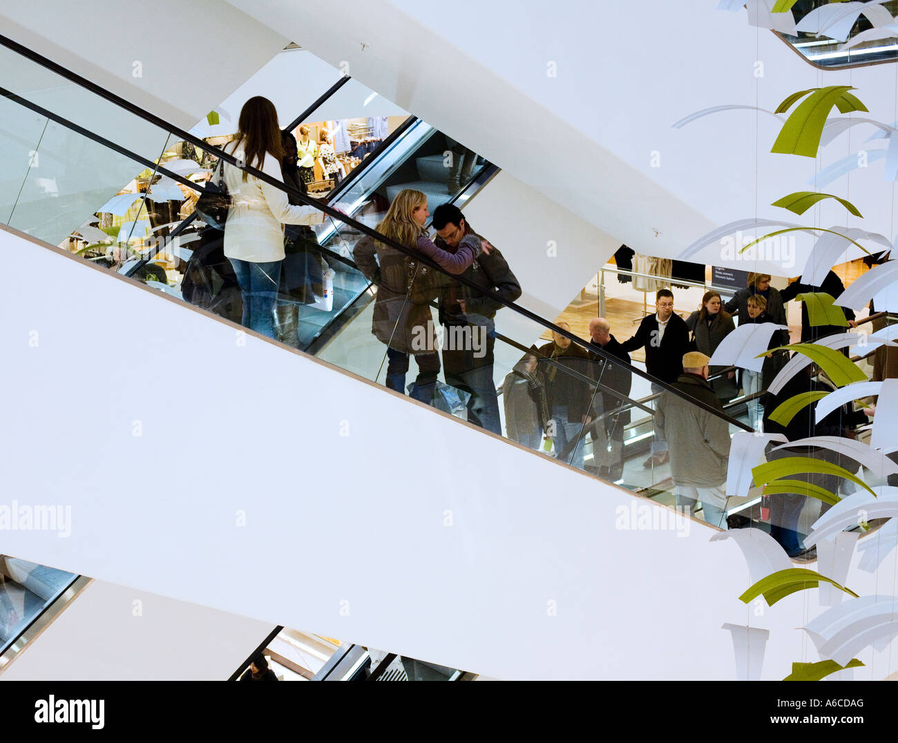 Young couple on escalators in West End department store during shopping trip London Stock Photo