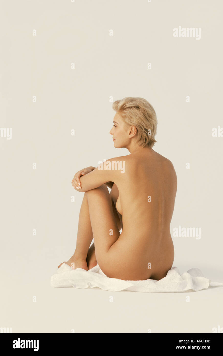 Side view of blond nude blond woman with short hair seated on white towel  on floor in studio Stock Photo - Alamy
