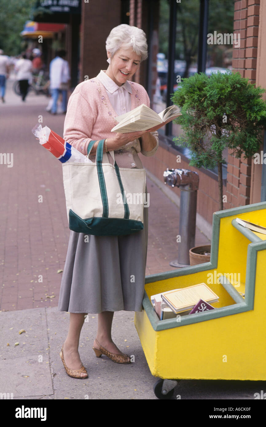 Mature woman shopping at an outdoors book stall Stock Photo