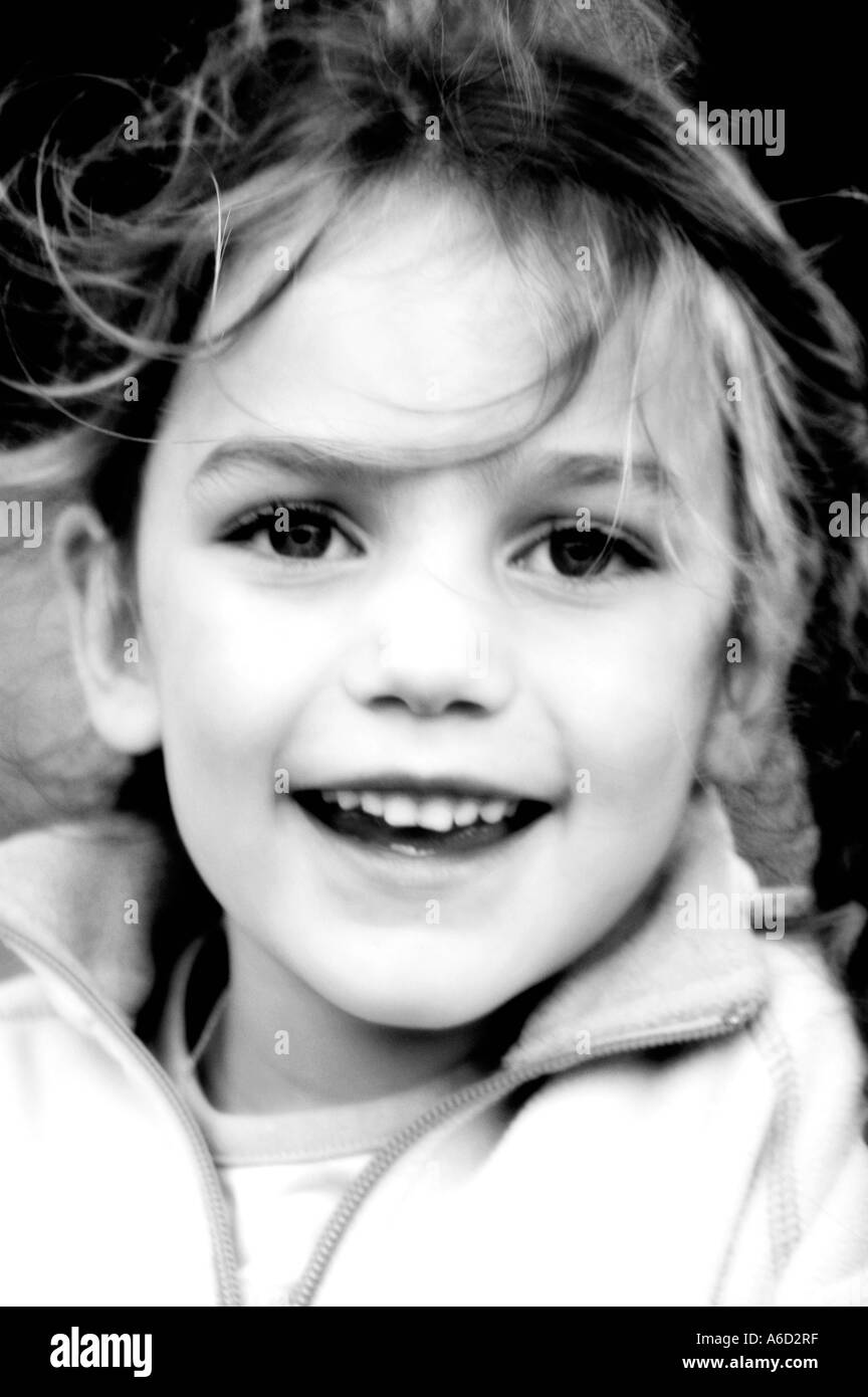 Young girl with wind blown hair smiling black and white Stock Photo