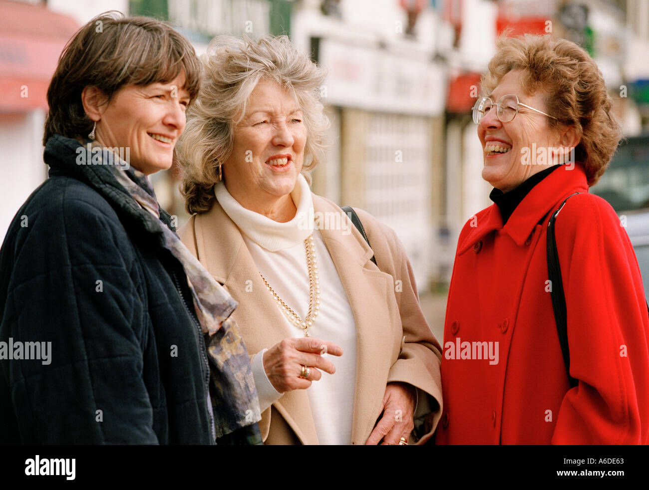 THREE MIDDLE AGED WOMEN CHATTING IN STREET Stock Photo