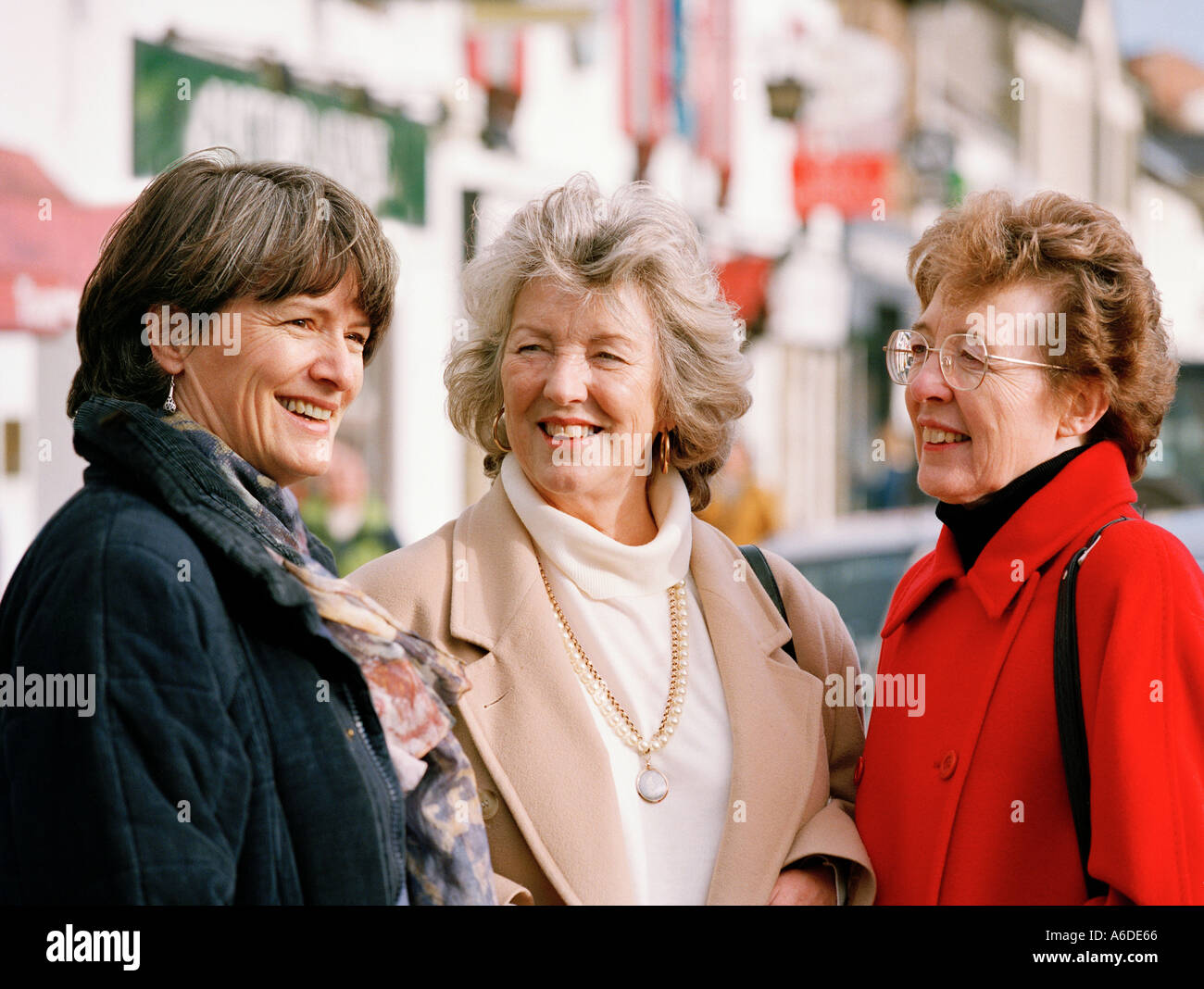 THREE MIDDLE AGED WOMEN CHATTING IN STREET Stock Photo