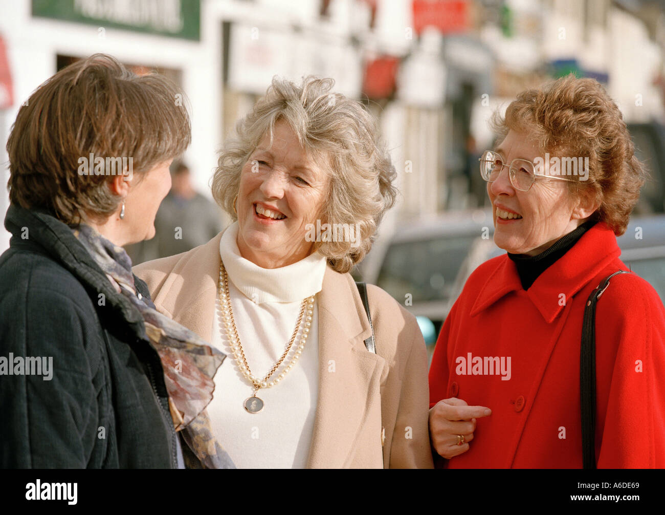 THREE MIDDLE AGED WOMEN CHATTING IN STREET UK Stock Photo