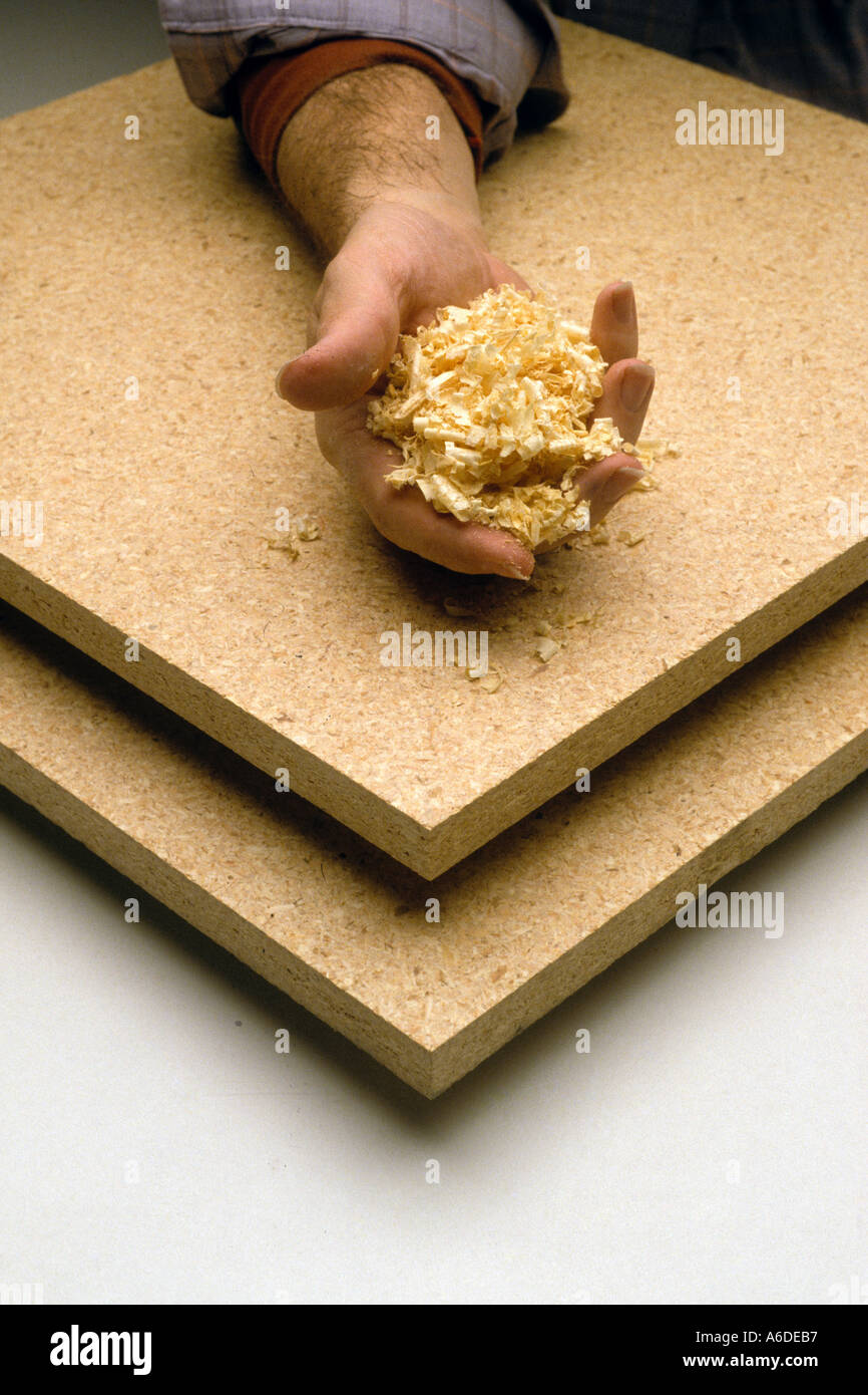hand holding wood particles which are compressed into particle board