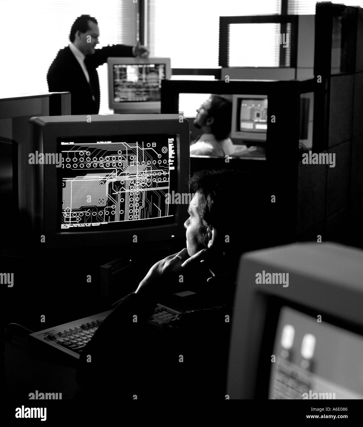 CAD operator looking at computer screen evaluating schematic in multi system office environment Stock Photo