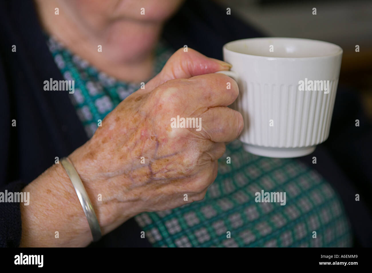 An elderly lady in her eighties drinks a cup of tea Stock Photo