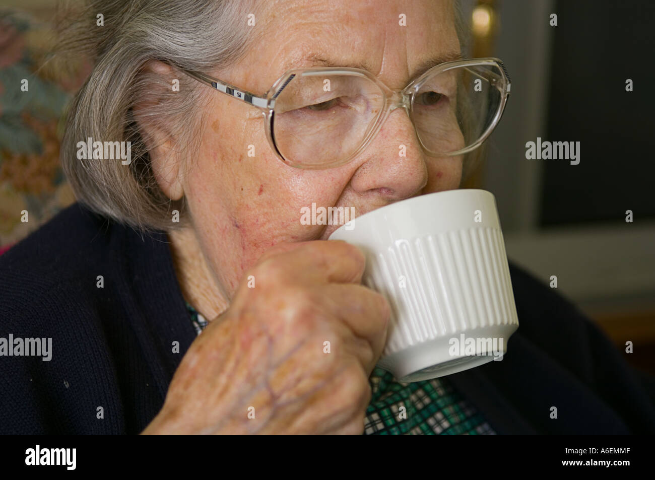 An elderly lady in her eighties drinks a cup of tea Stock Photo