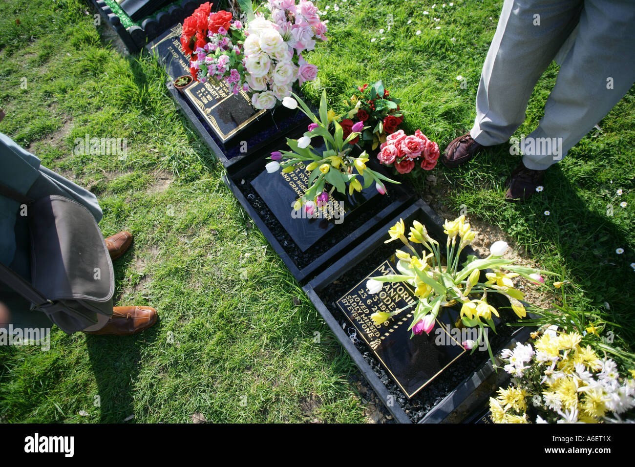 Family members paying their respects by the grave of a loved one at a cemetary, Essex, England, UK. Stock Photo