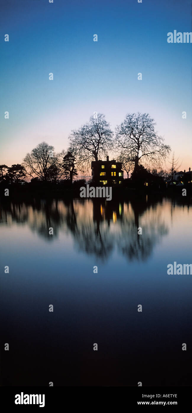 House set amongst trees on the banks of the River Thames London at dusk Stock Photo