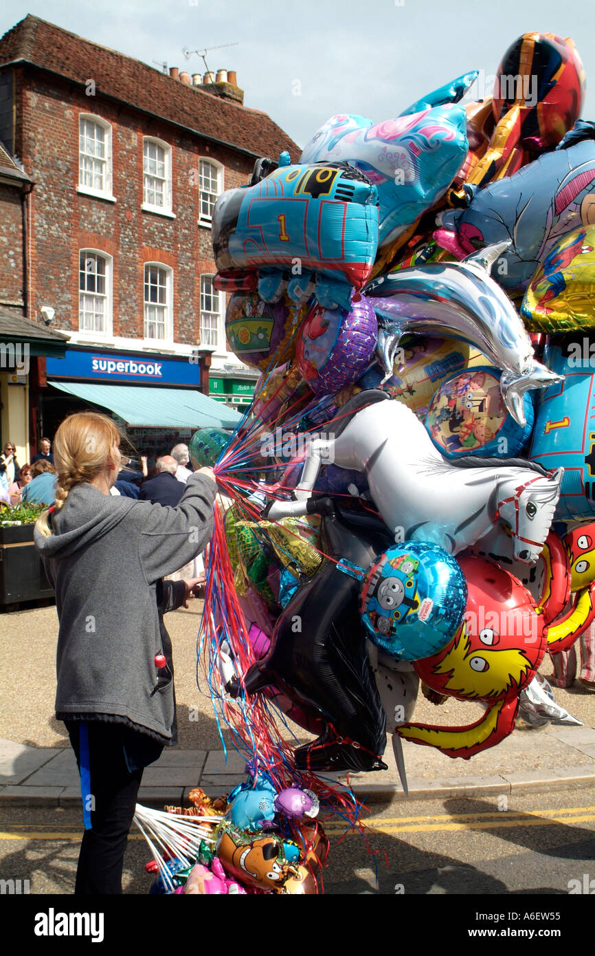 Street seller holding a mass of helium filled metal foil balloons. Stock Photo