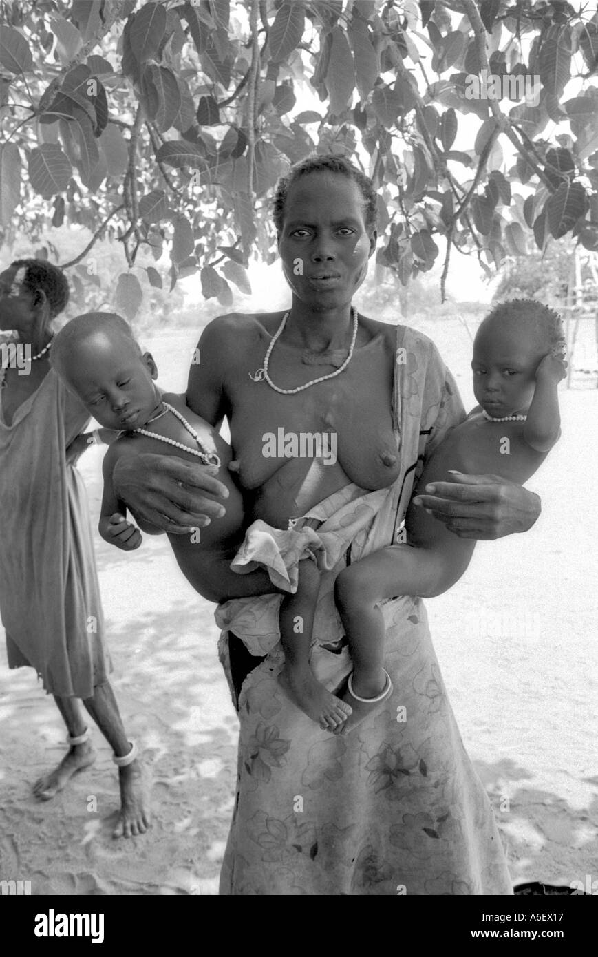 B/W portrait of a displaced mother and twins at a feeding centre, Bahr al Ghazal, South Sudan Stock Photo