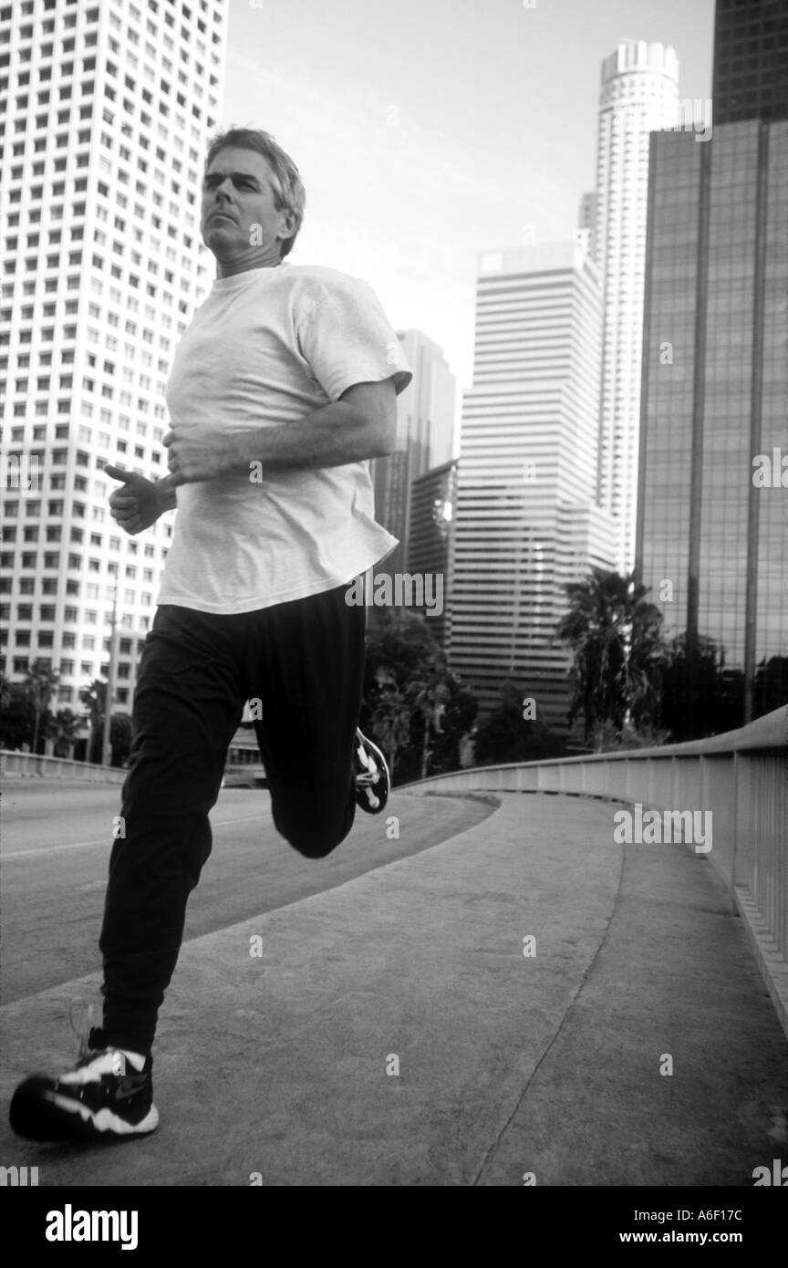 Mature man jogging in downtown w skyscrapers in background  Stock Photo