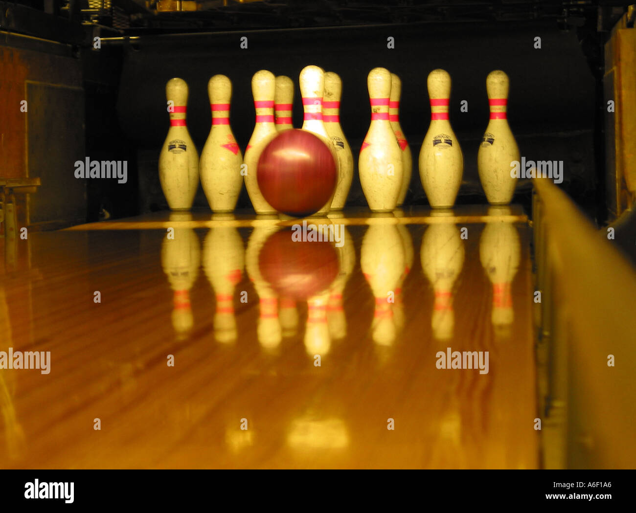 Ten-pin bowling, bowling ball rapidly approaching standing pins at the end of a indoor bowling wooden lane, bowling in a bowling alley Stock Photo