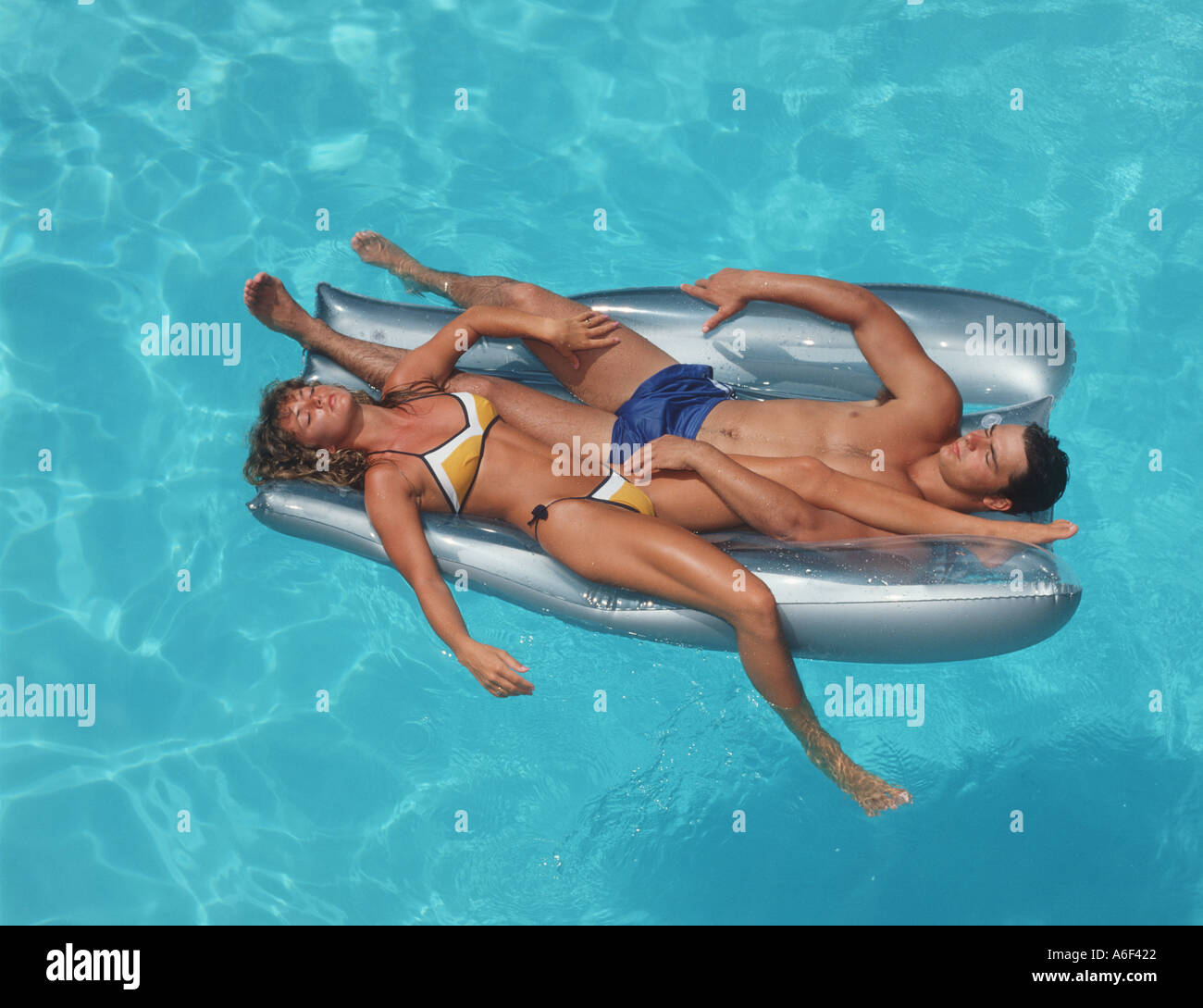couple relaxing on raft in swimming pool Stock Photo