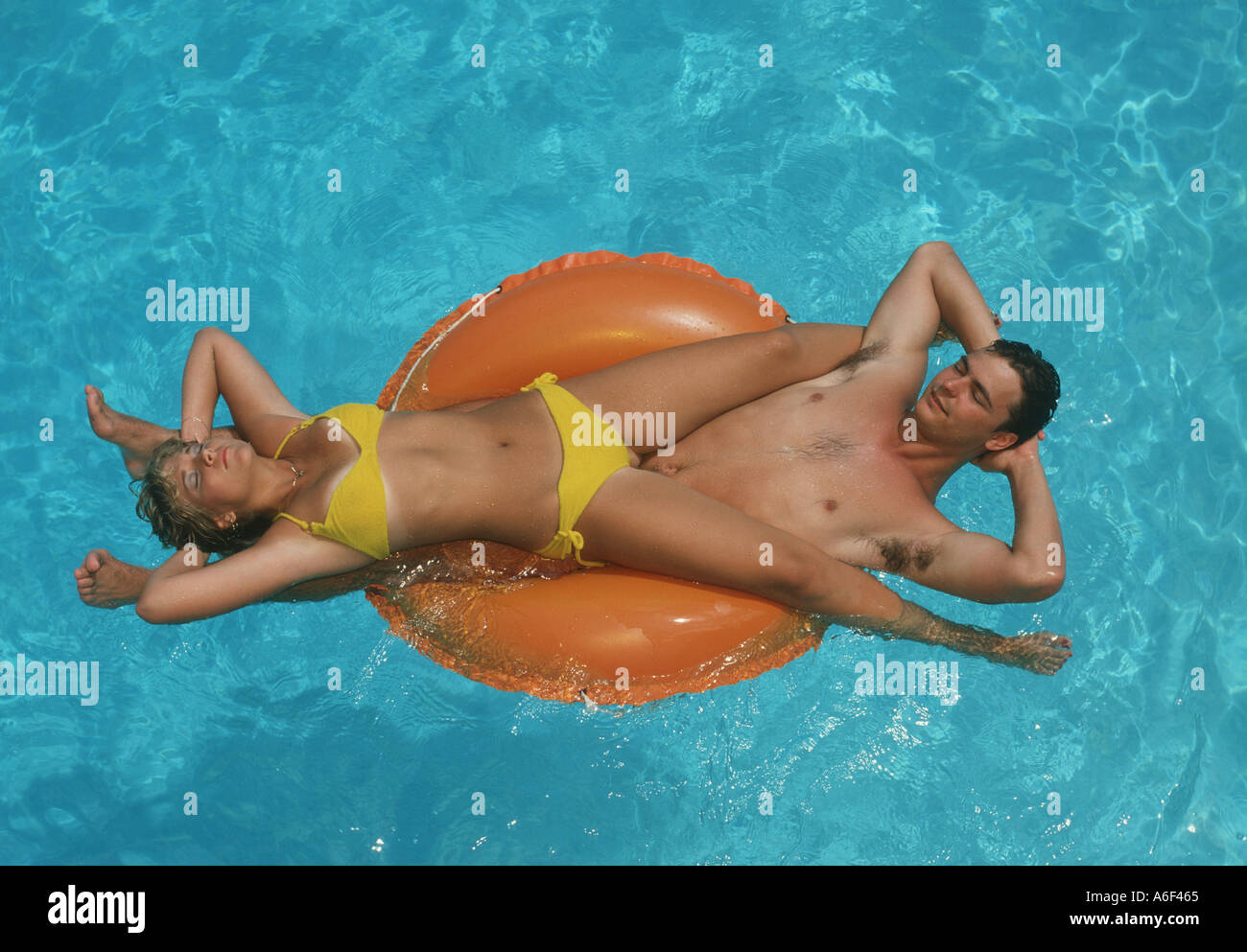 couple relaxing on inner tube in swimming pool Stock Photo