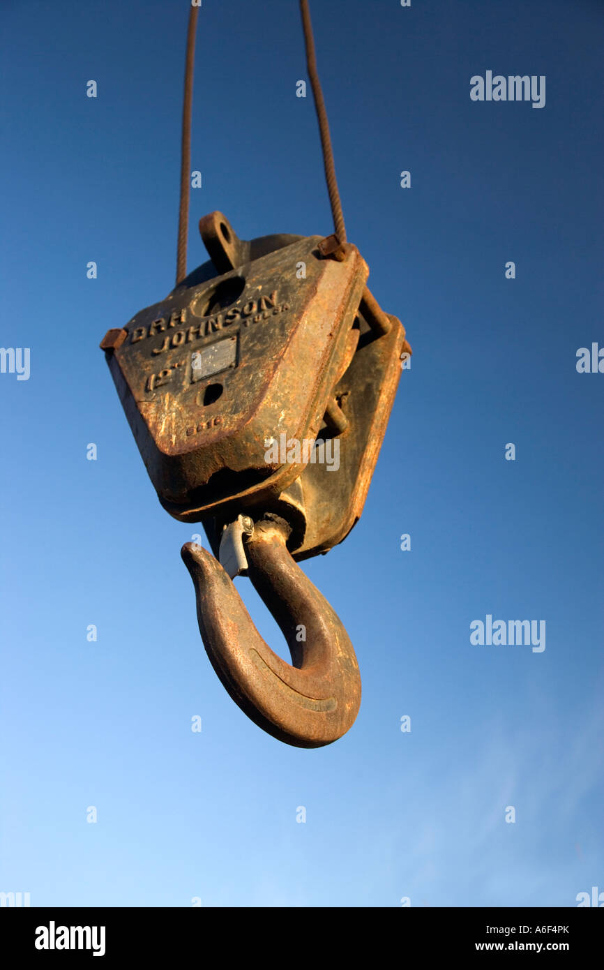 Old rusty pulley hook hanging from cable. Stock Photo