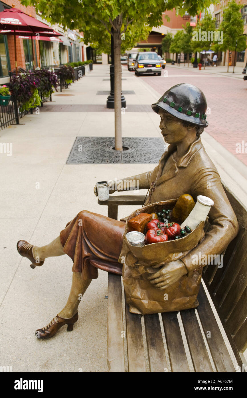 ILLINOIS Chicago Adult woman sit on bench holding paper bag of groceries statue in old Maxwell Street market area Stock Photo