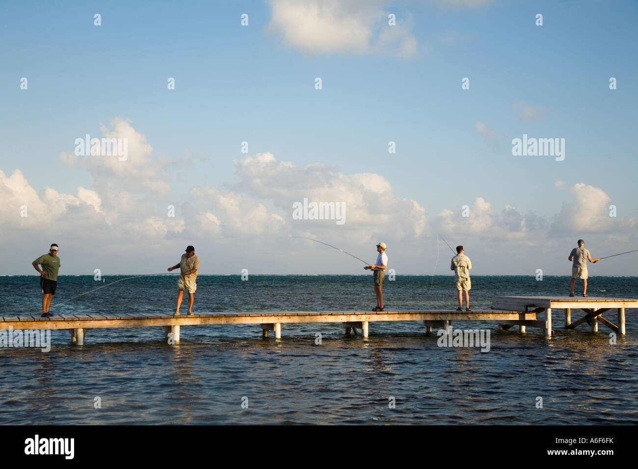 BELIZE Ambergris Caye Five adult men practice fly fishing from dock and