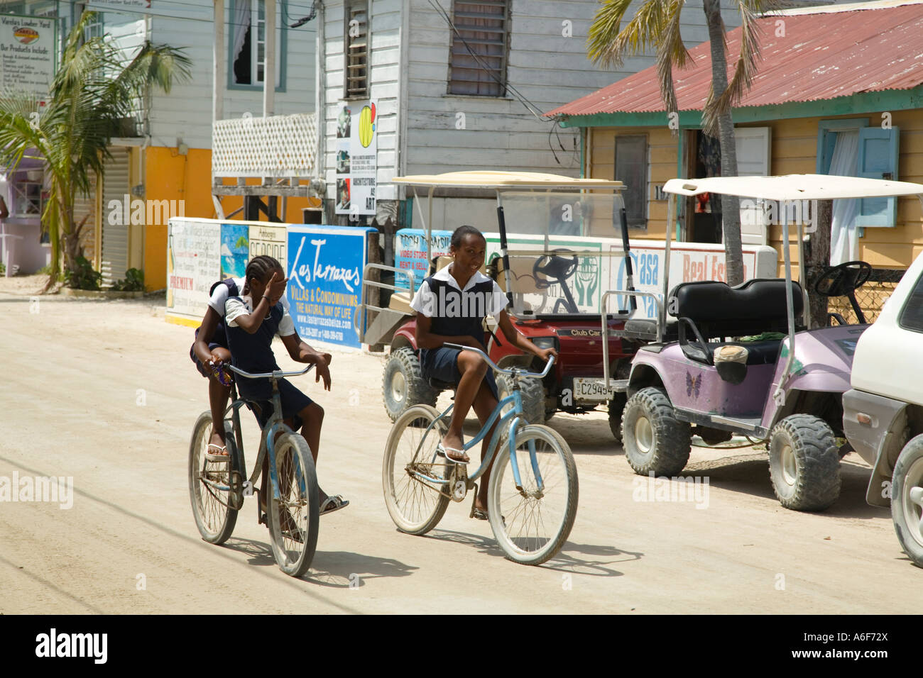 BELIZE San Pedro on Ambergris Caye School children in uniforms head home for lunch bicycle down town street Stock Photo