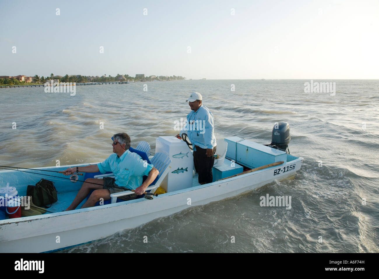 BELIZE Ambergris Caye Adult male fly fisherman sit in chair on panga boat guide drive boat