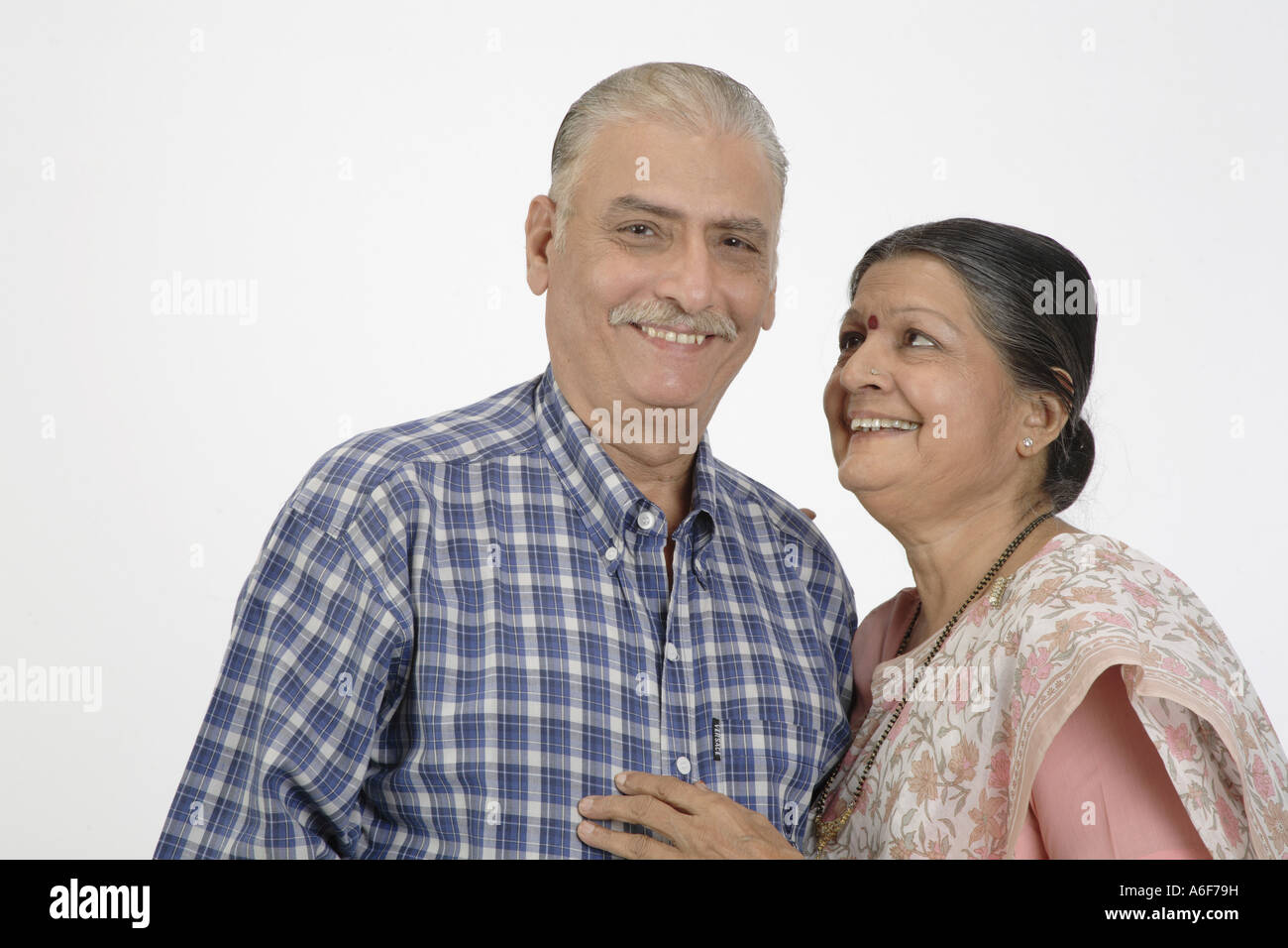 Old couple smiling lady kept her right hand on the shoulder and other on his chest looking at him and smiling Stock Photo